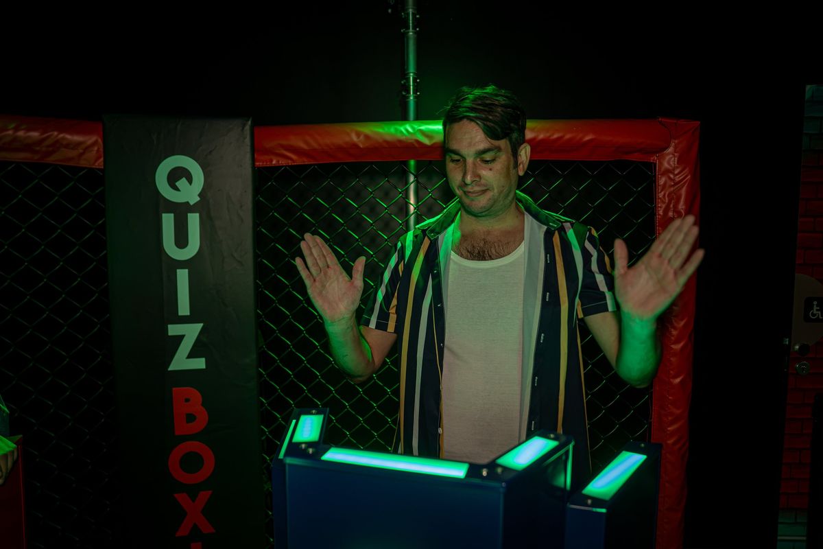 Joueur derrière son pupitre sous l'éclairage vert de l'arène du Quiz Boxing au Space Bowling Nîmes