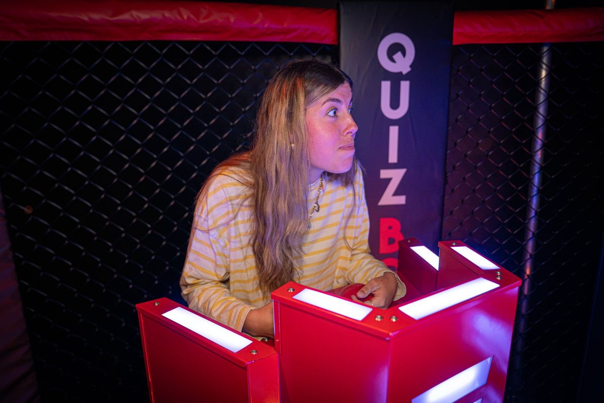 Joueuse concentrée devant son pupitre à buzzer, éclairage rouge de l'arène du Quiz Boxing à Nîmes